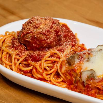 Spaghetti with a meatball and lasagna on a plate, close up.