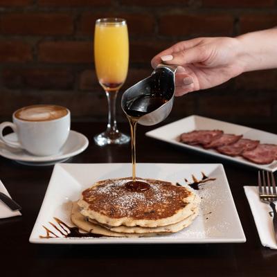 Pouring syrup on pancakes.
