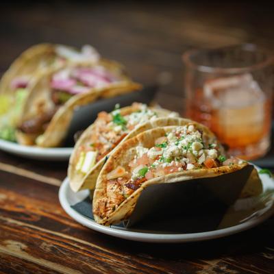 A dish of gourmet tacos served alongside a cocktail.