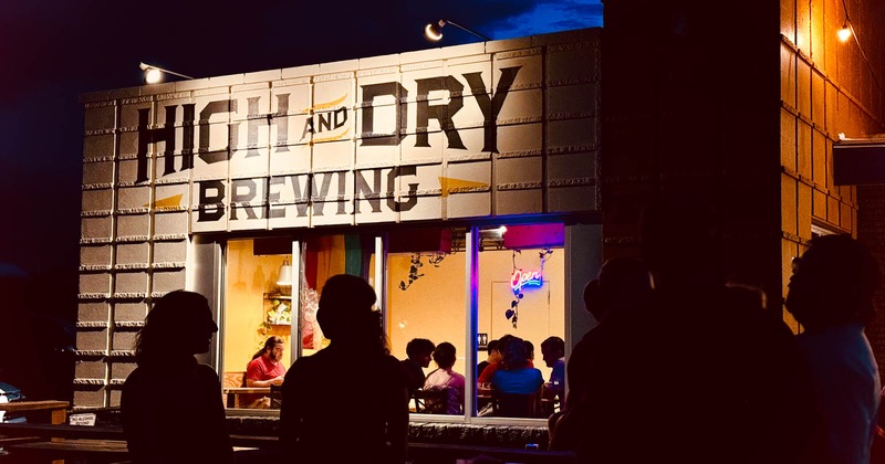 People gathered outside and inside High and Dry Brewing, enjoying the evening ambiance