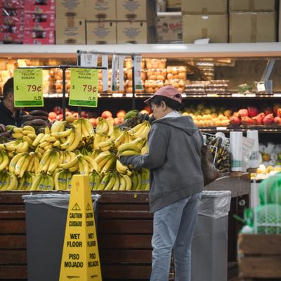Customers shopping for bananas at the produce section.