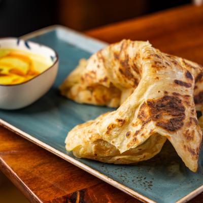 Fresh roti with curry dip on a blue plate.