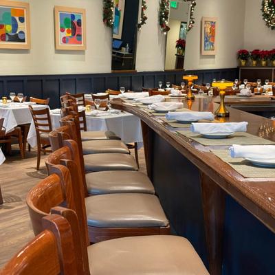 Interior with a bar area with stools and a dining area with tables set for guests.