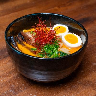 Bowl of spicy tantanmen ramen with soft-boiled egg and chili thread garnish.