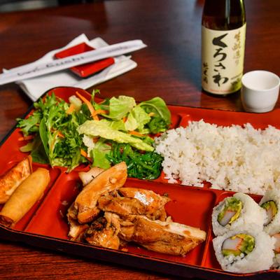 Teriyaki Chicken, with salad, sushi rolls, rice, dumpling, and egg roll.