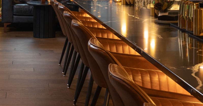 Festively decorated bar with a long countertop, leather stools, and holiday decorations