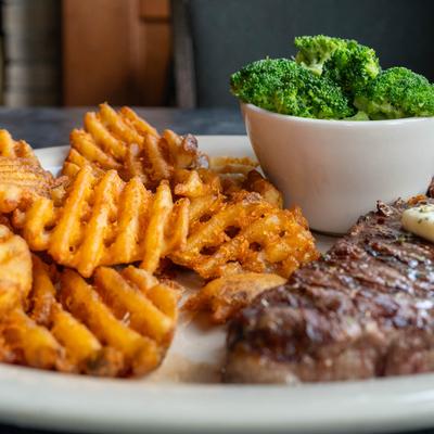KC Strip Steak served with waffle fries and broccoli on the side.