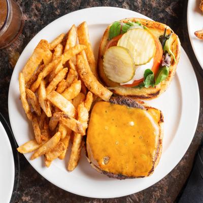 Angus beef burger served with fries on a white plate.