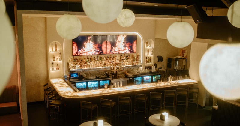 Interior, bar area, marble top bar with stools, drink shelves, TVs on the wall