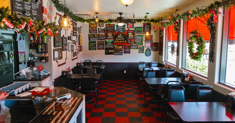 Interior of a holiday-decorated cafe with checkered floors, menu boards, and tables