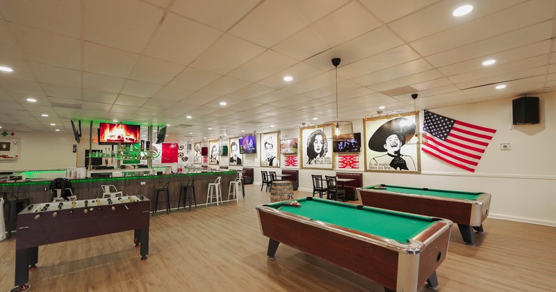 Interior, wide view, pool tables and table football with bar in the background