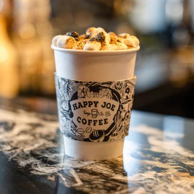 Hot chocolate topped with toasted marshmallows, serv ed in a branded paper cup.