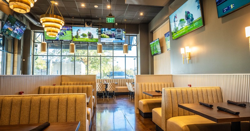 Interior, wide view of dining area, TV screens on the wall