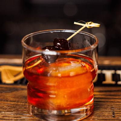 Manhattan cocktail on the rocks, with cherries garnish.