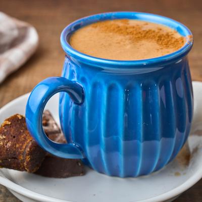 Mexican hot chocolate served in a blue mug and sprinkled with cinnamon.