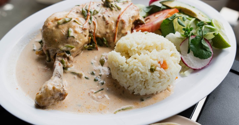 Creamy chicken served beside rice, salad, and tortillas