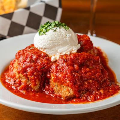 Meatballs in tomato sauce topped with ricotta cheese.