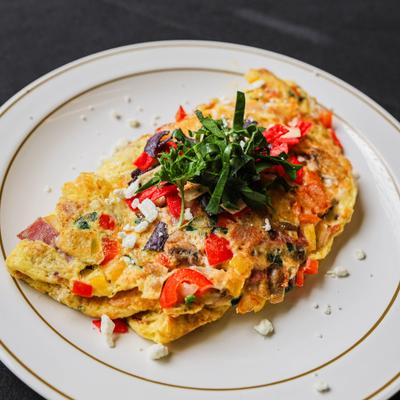 Vegetable omelette topped with cheese crumbles and fresh herbs.