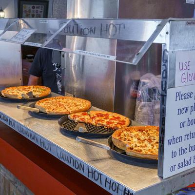 Assorted pizzas in a glass display.