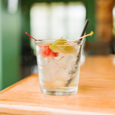 Clear cocktail garnished with lime and cherry.