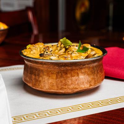 Chicken curry served in a hammered copper bowl.