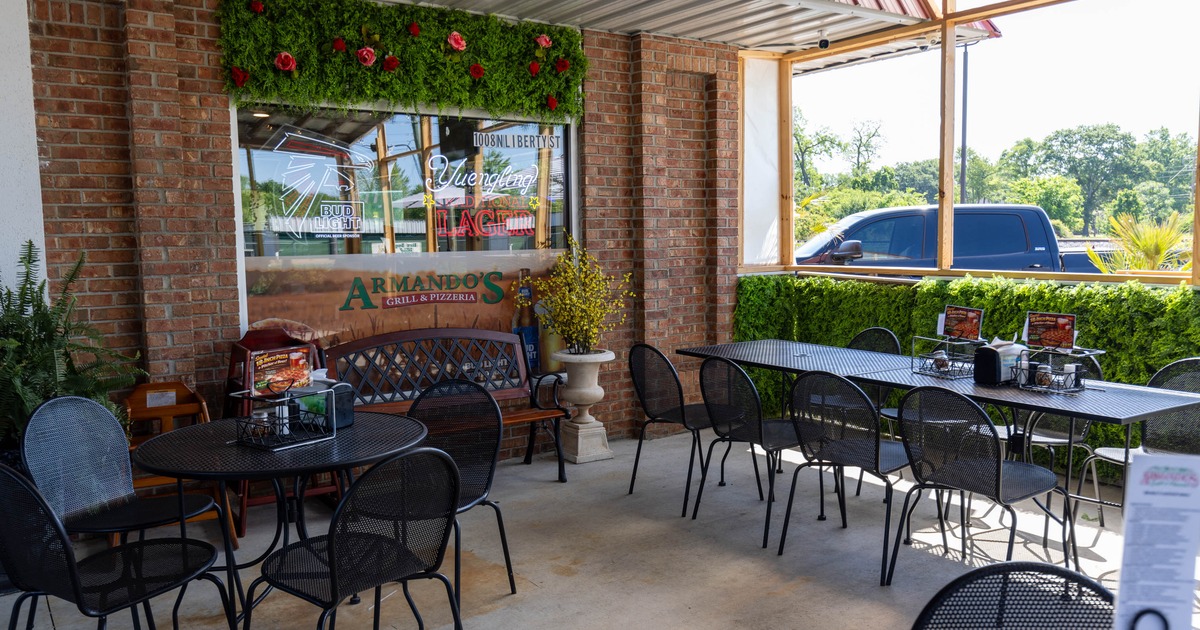Outdoor seating area at Armando's Grill & Pizzeria - tables, chairs, a greenery wall