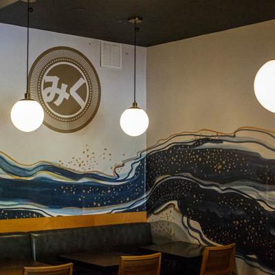 Interior with tables, chairs, pendant lights, and a mural.