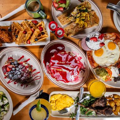Various dishes and drinks spread on a wooden table, top down view.