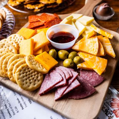 Charcuterie board with assorted meats, cheeses, crackers, and olives.