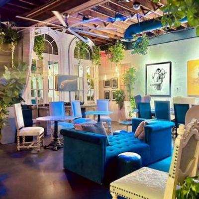 Cozy interior with blue velvet seating, white tables and chairs, and greenery decor.