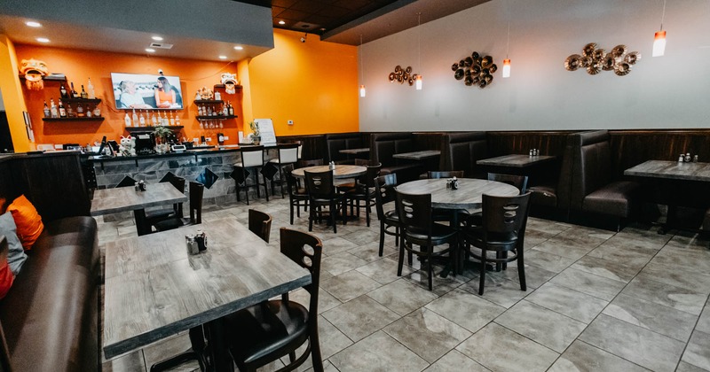 Interior, dining area, tables and chairs ready for guests, booths, bar with stools in the back