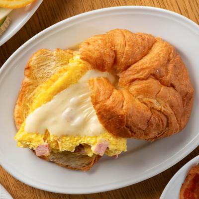 Croissant sandwich with scrambled eggs, ham and melted cheese.