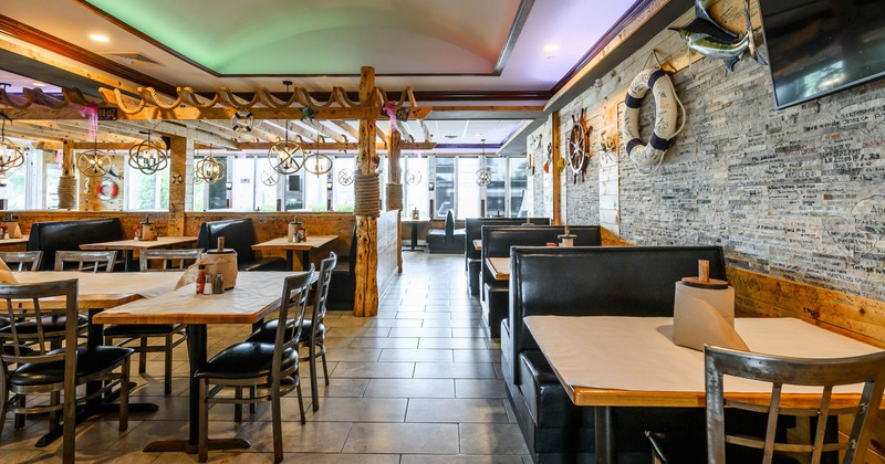 A nautical-themed interior - wooden beams, leather booths, ship wheel light fixtures.