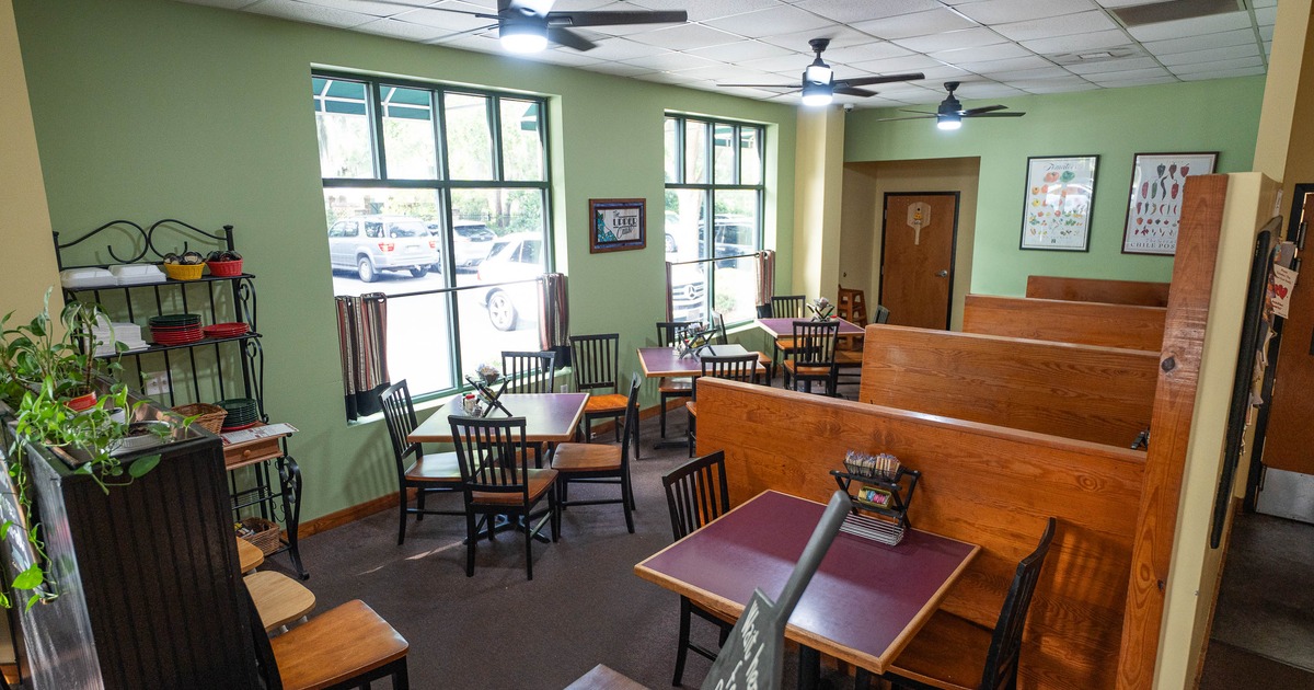 Cozy café interior with light green walls, wooden booths, and black chairs