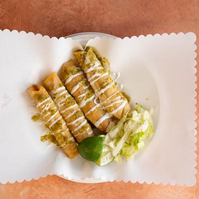 Crispy flautas topped with sour cream and pesto.
