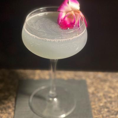 A glass of cocktail decorated with a flower