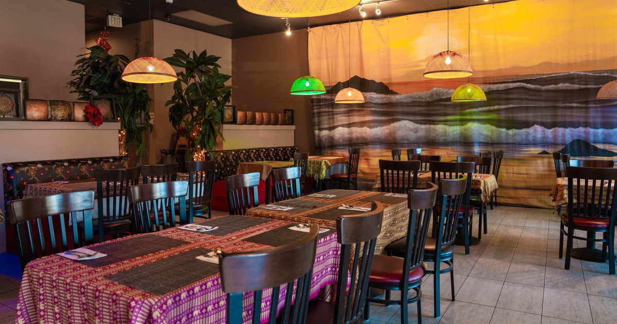 Interior, colorful tablecloths, dark wooden chairs, pendant lights, large seascape mural