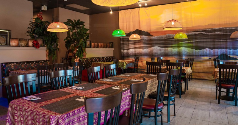 Interior, colorful tablecloths, dark wooden chairs, pendant lights, large seascape mural