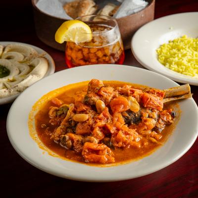 Lamb Shank plate with assorted dishes and a glass of iced tea.