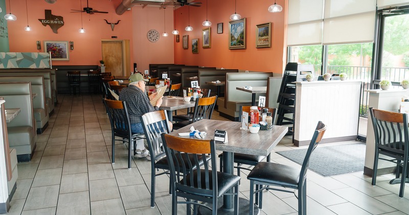 Interior dining area with upholstered booths along the walls and tables and chairs in the middle