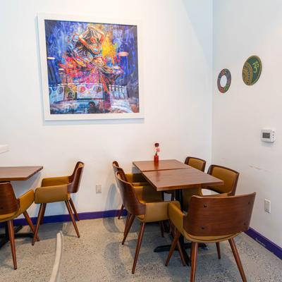 Interior, tables and chairs, a colorful painting and decorative mandalas on the walls.
