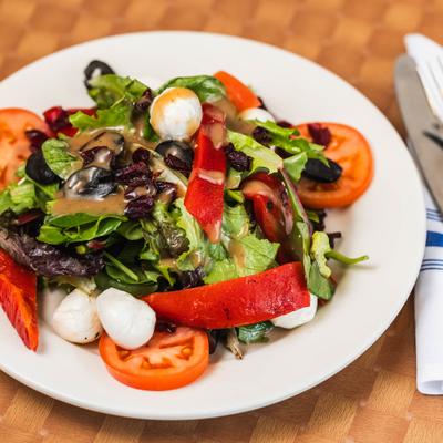 Mixed green salad with mozzarella, tomatoes, olives.