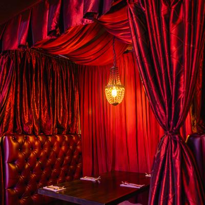 A separated seating area with upholstered benches and decorative curtains.