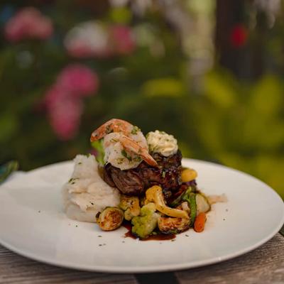 Surf and Turf dish featuring a steak accompanied by seafood and sides.