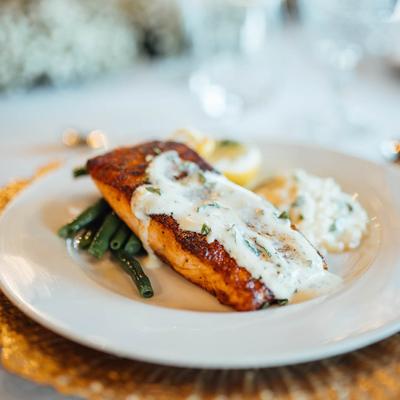 Seared salmon topped with sauce, served with green beans and risotto.