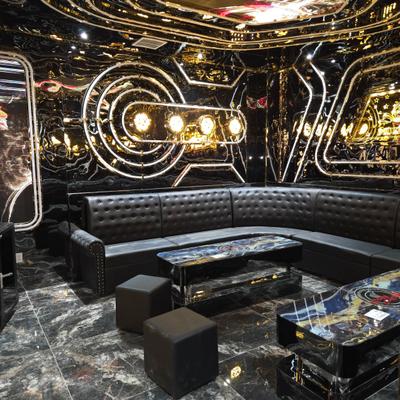 A luxury karaoke room featuring high-gloss black walls, lounge seating, and dark marble flooring.