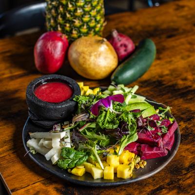 Sabor Riviera salad with dressing, alongside fresh fruit on the table.