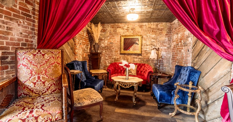 Intimate vintage seating area with red sofa, blue armchairs and brick walls.