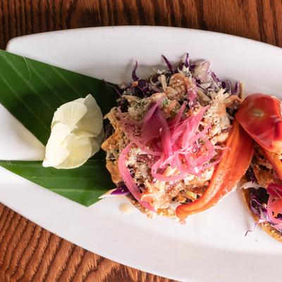 Tostadas, with beans, cabbage, chicken, pickled red onion, sour cream, avocado, and cheese.