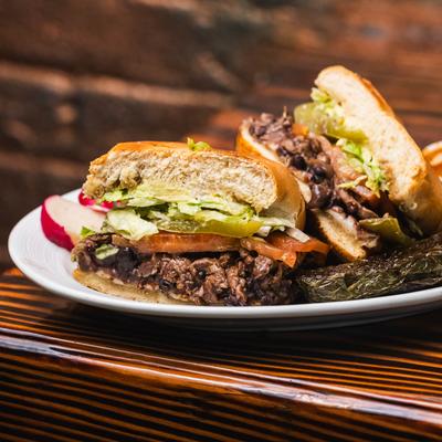 Torta sandwich with beef, tomato, lettuce, pickle, and black beans.